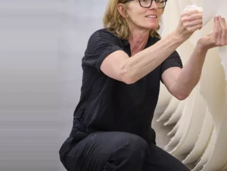Künstlerin Angela Glajcar bei der Werkinstallation, hockend vor einer grossformatigen Papierarbeit