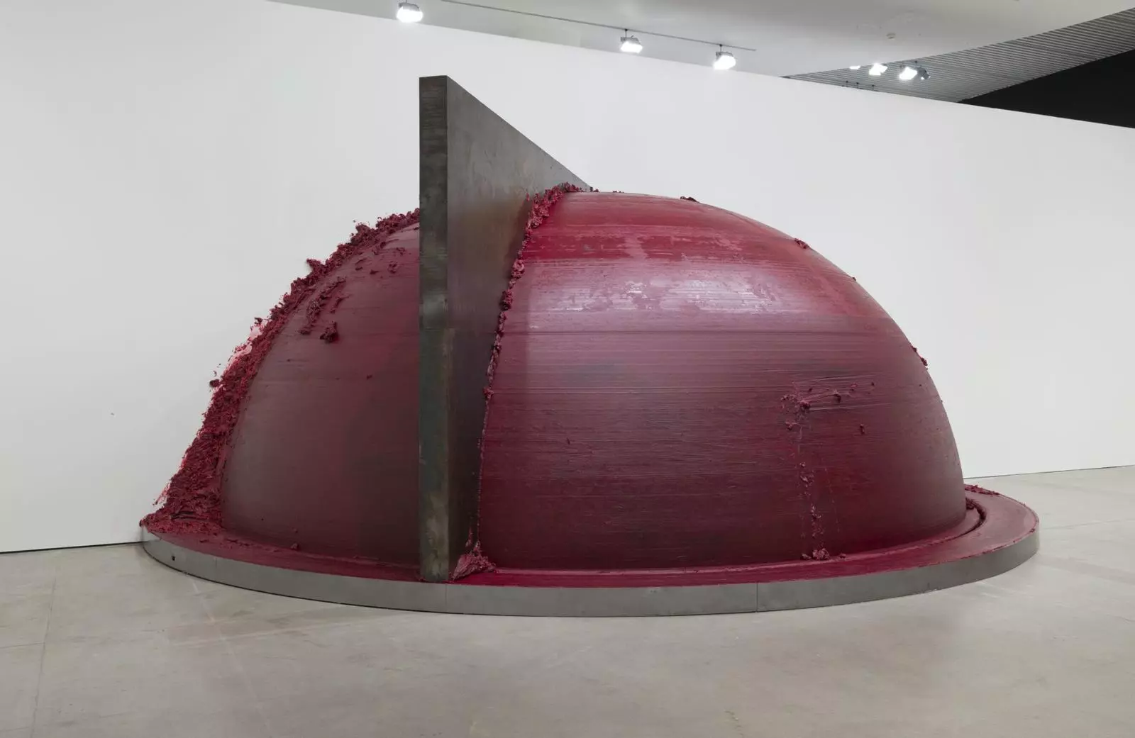 Anish Kapoor Duisburg – Grossformatige Skulptur: dunkelrote Halbkugel mit metallener Klinge, die die Oberfläche durchschneidet, Pigmentreste am Rand