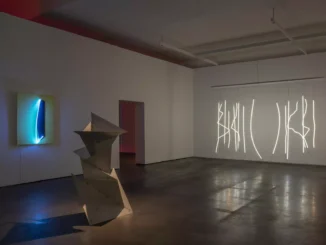 Ausstellungsansicht mit Metallskulptur, Neon-Wandobjekt und Lichtinstallation in dunklem Galerieraum