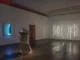 Ausstellungsansicht mit Metallskulptur, Neon-Wandobjekt und Lichtinstallation in dunklem Galerieraum
