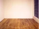 Minimalistische Bodeninstallation: weisser Kreisumriss auf Holzdielen in leerem Galerieraum mit Sprossenfenster