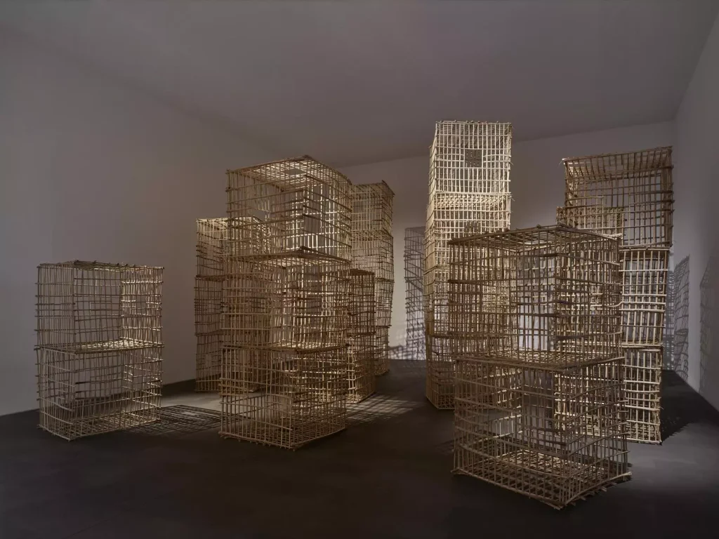 Rauminstallation aus gestapelten Holzgitterkäfigen, die turmhohe Strukturen im weissen Galerieraum bilden
