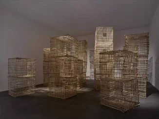 Rauminstallation aus gestapelten Holzgitterkäfigen, die turmhohe Strukturen im weissen Galerieraum bilden
